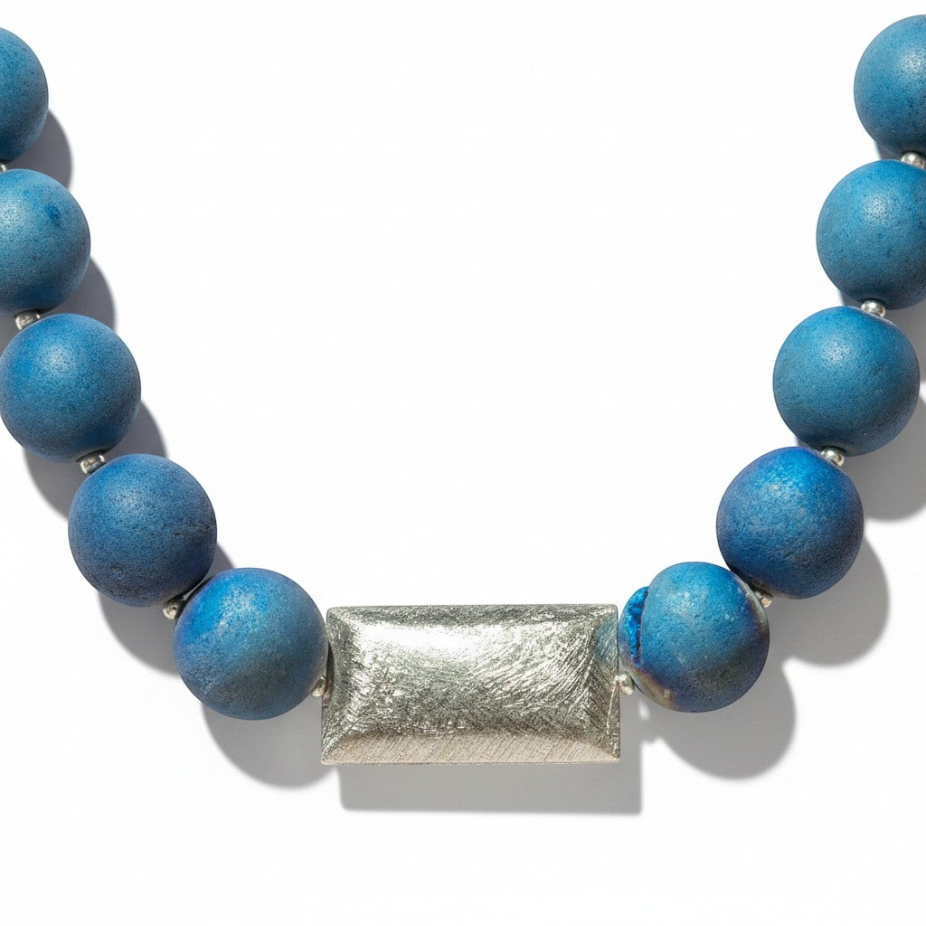 Eine elegante Halskette aus blauen Geoden-Achatperlen mit einem rechteckigen Mittelstück aus 925er Silber und dezenten Geoden Mustern.