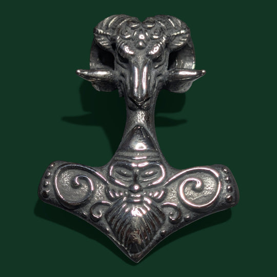 Ein silberfarbener Anhänger aus Edelstahl von Sinnikäs, der einen Widderkopf auf Thors Hammer zeigt und mit aufwendigen, von den Wikingern inspirierten Details verziert ist.