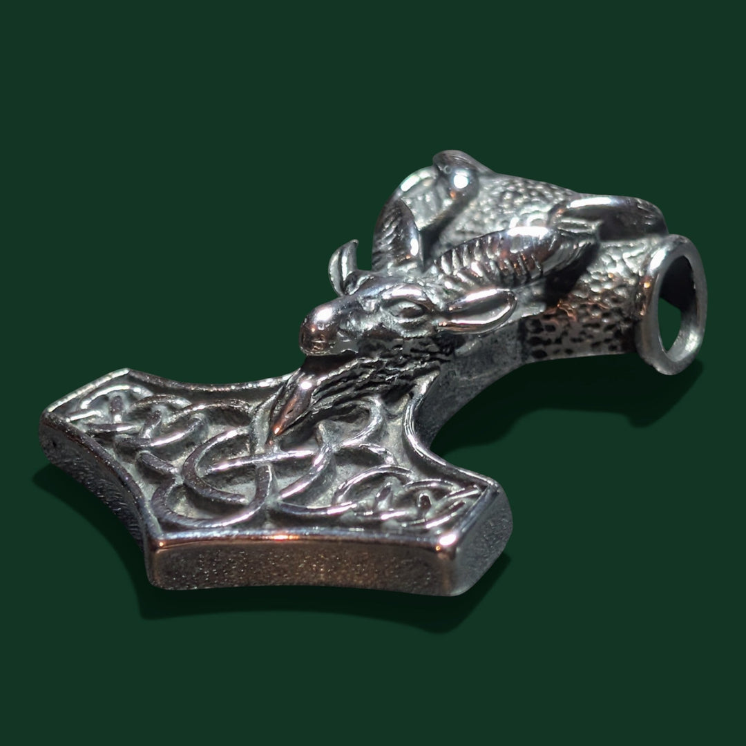 Sinnikäs-Anhänger aus silberfarbenem Edelstahl in Form eines Ziegenkopfes auf einem Thorshammer mit keltischen Knotenverzierungen.