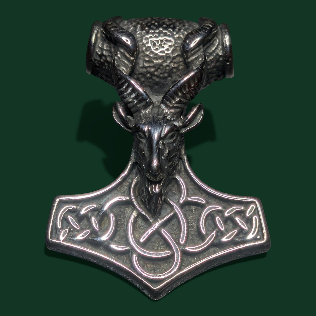 Ein stilvoller Anhänger aus silberfarbenem Edelstahl mit einem detailreichen Ziegenkopf auf einem Thor-Hammer-Motiv mit keltischen Knotenmustern.