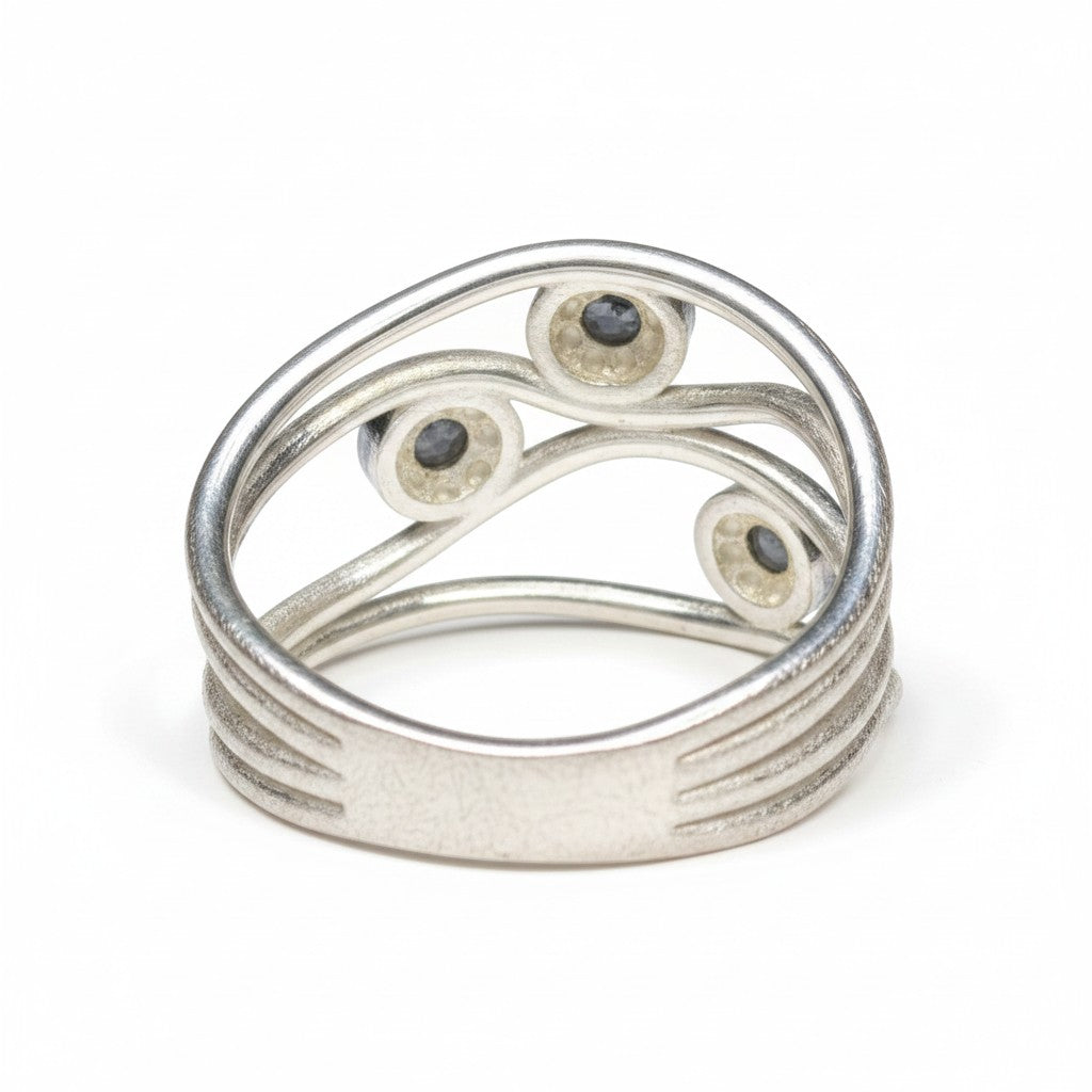 Sinnikäs Ring aus 925er Silber mit drei kleinen, dunklen Labradorit-Steinen in geschwungener Fassung. Größe 58.