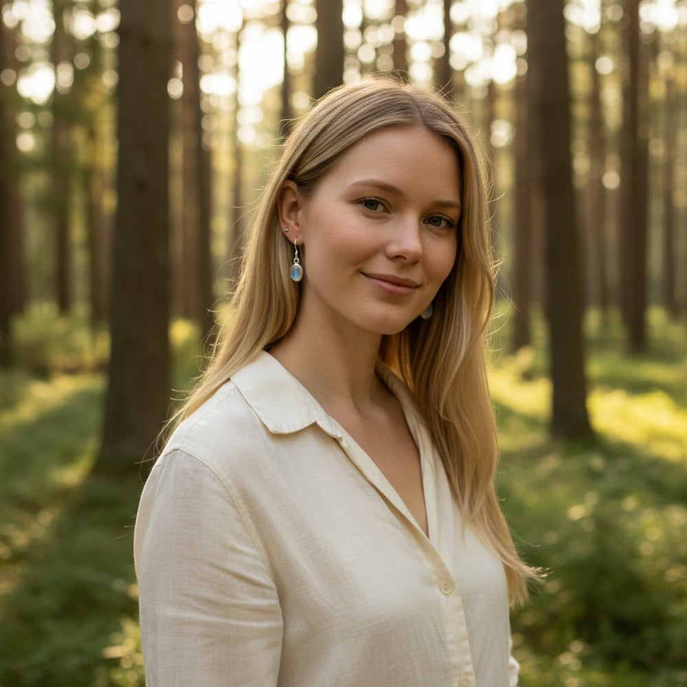 Sinnikäs Mondstein Ohrhänger aus Sterling-Silber mit schimmerndem Mondstein und rhodinierter Oberfläche, getragen von einer Frau im Wald.