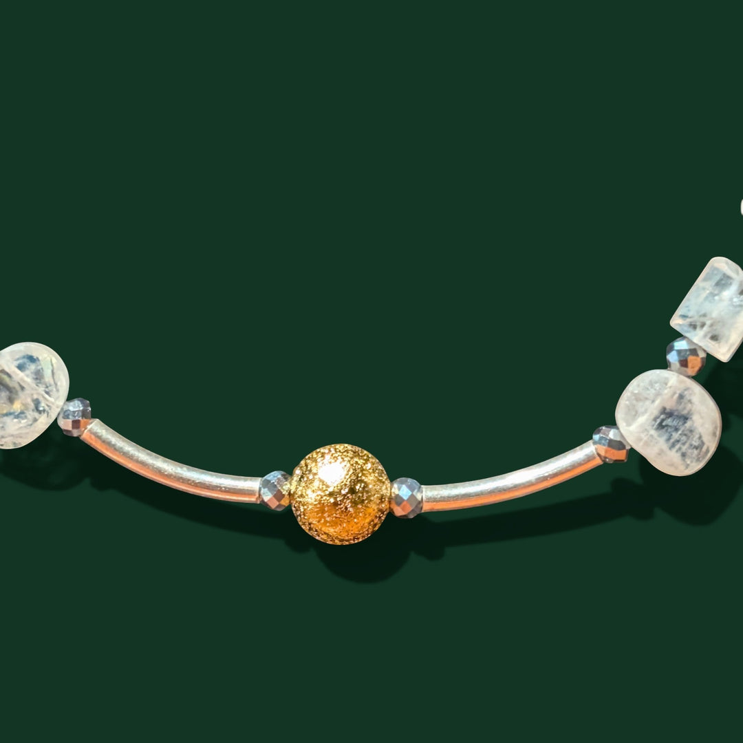 Sinnikäs necklace with faceted moonstone, silicon beads, and a gold-plated ball on a silver cord.