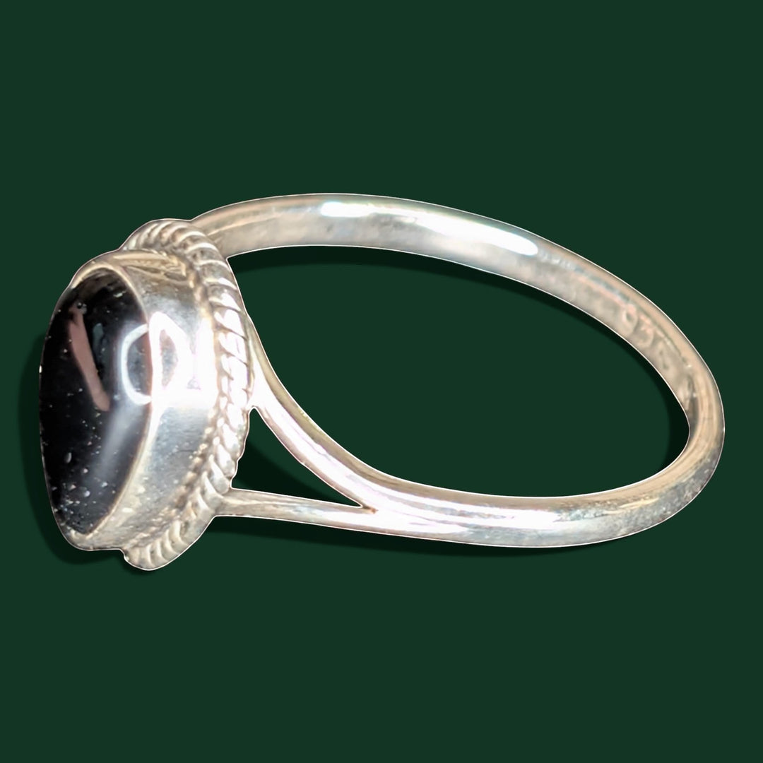 Ein stilvoller Ring aus Sterlingsilber mit einem tropfenförmigen Stein aus schwarzem Obsidian, der in einer Zierfassung im Seilstil gefasst ist.