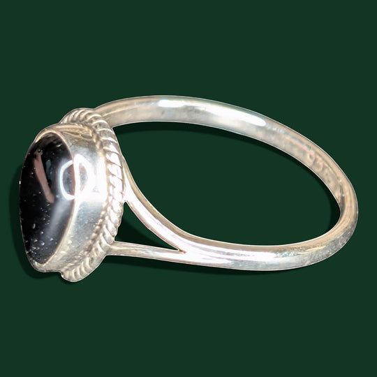 Ein stilvoller Ring aus Sterlingsilber mit einem tropfenförmigen Stein aus schwarzem Obsidian, der in einer Zierfassung im Seilstil gefasst ist.