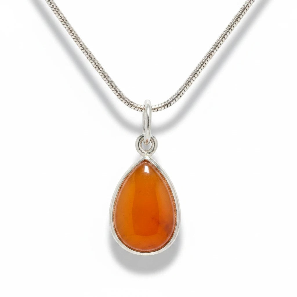 Sinnikäs Anhänger aus 925er Silber mit tropfenförmigem, orangefarbenem Karneol an einer silbernen Schlangenkette.
