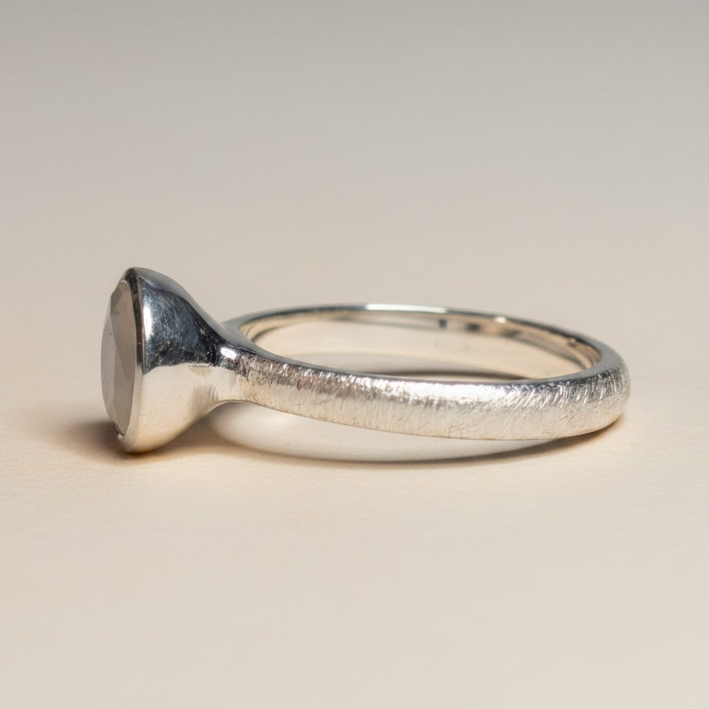 Sinnikäs Silberring mit einem facettierten Mondstein-Cabochon, matt gebürstetes Band.